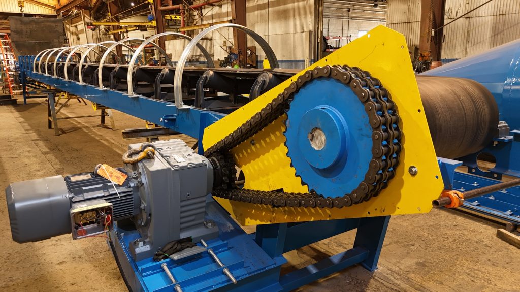 Channel frame belt conveyor with chain drive under assembly in fabrication shop