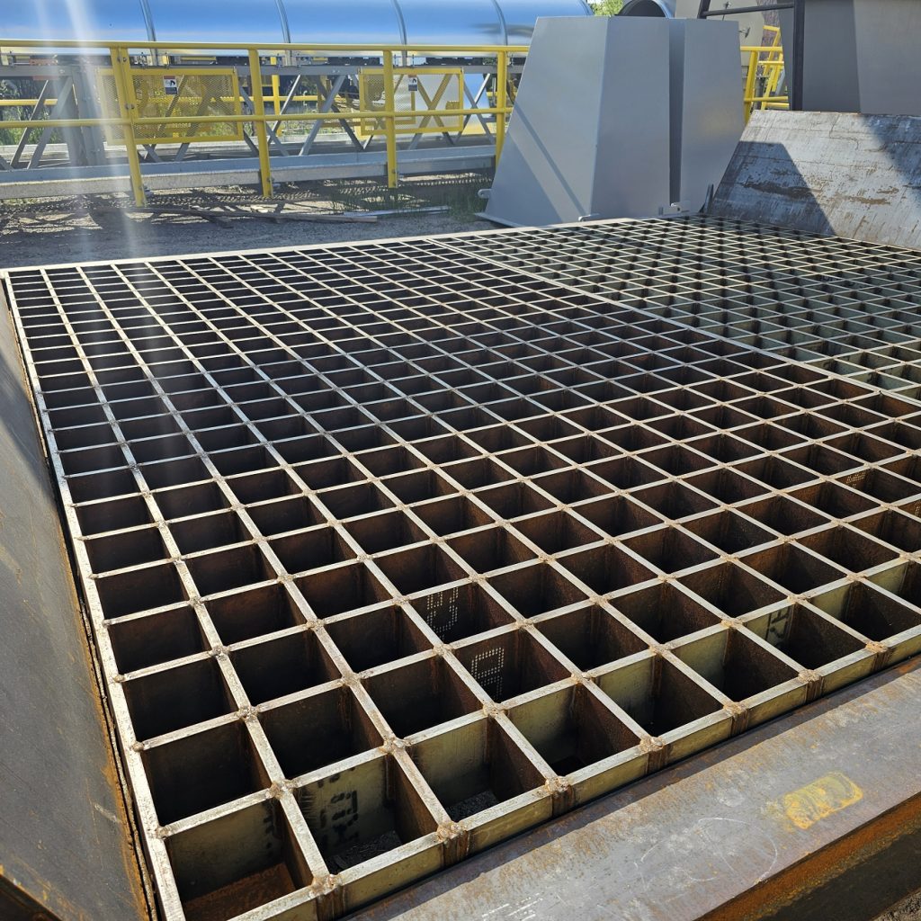 Heavy-duty hydraulic grizzly grid over hopper for bulk material handling